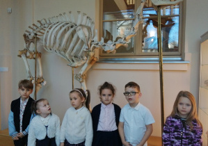 Dzieci stoją przed szkieletem zwierzat